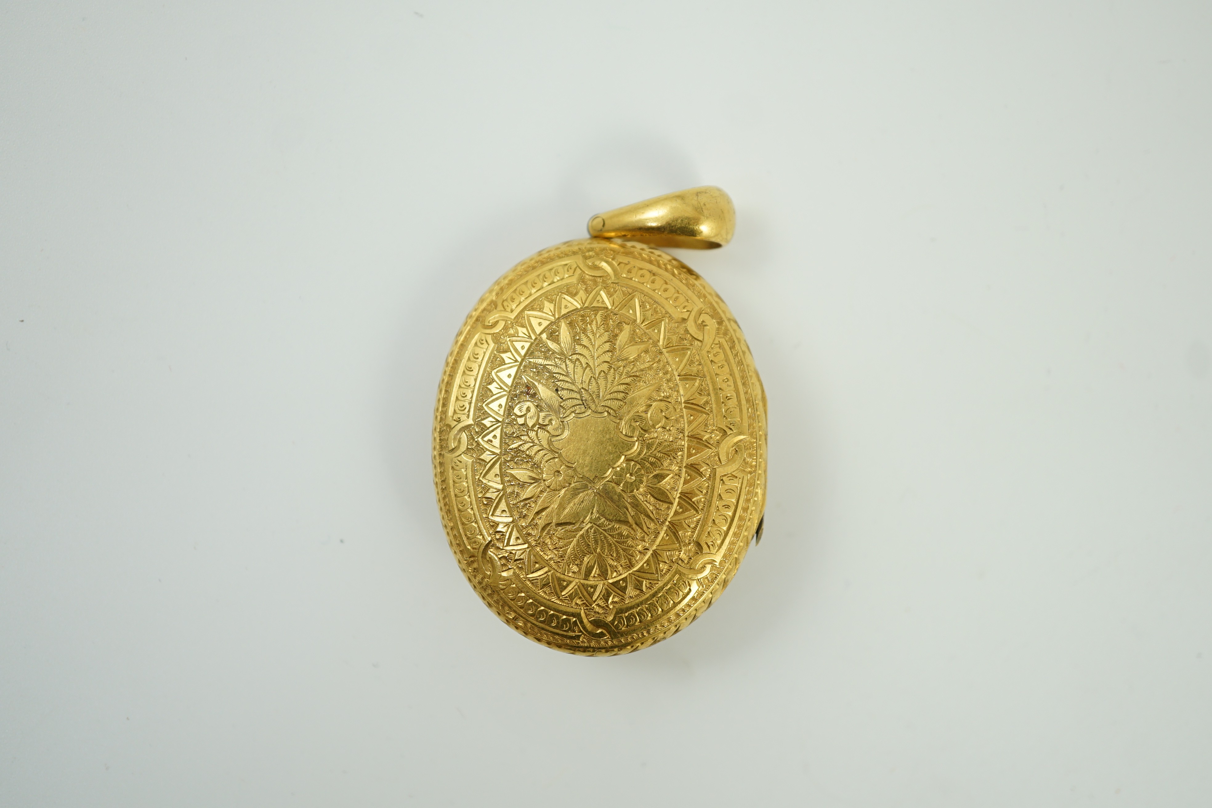 A Victorian engraved yellow metal, blue enamel and seed pearl set oval locket, 45mm, gross weight 21.2 grams.